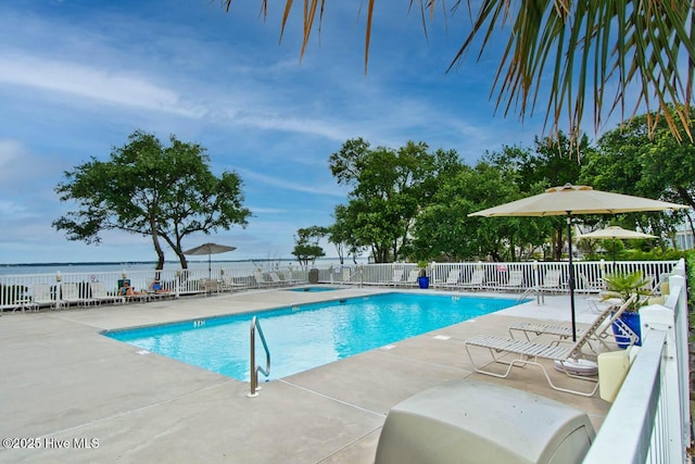 community pool featuring a water view, a patio area, and fence