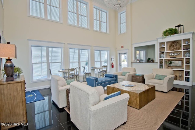 living area with dark tile patterned floors, a towering ceiling, and baseboards