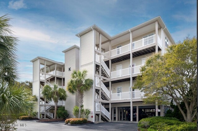 view of building exterior with driveway, stairs, and a carport