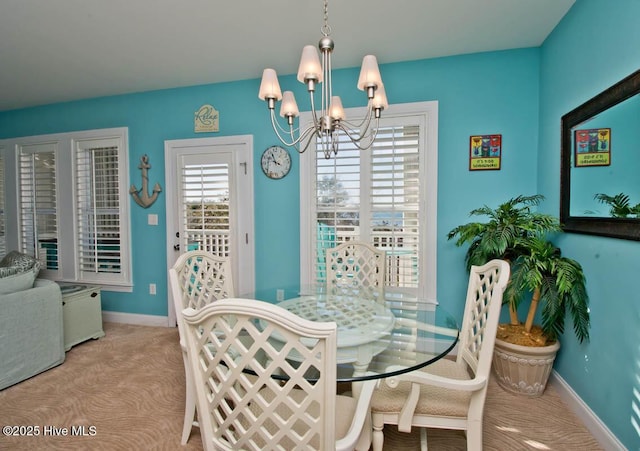 dining room with light colored carpet, a notable chandelier, and baseboards