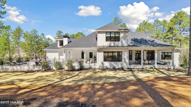 rear view of property featuring a patio, fence, board and batten siding, and roof with shingles