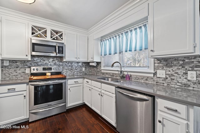 kitchen with appliances with stainless steel finishes, dark countertops, white cabinetry, and a sink