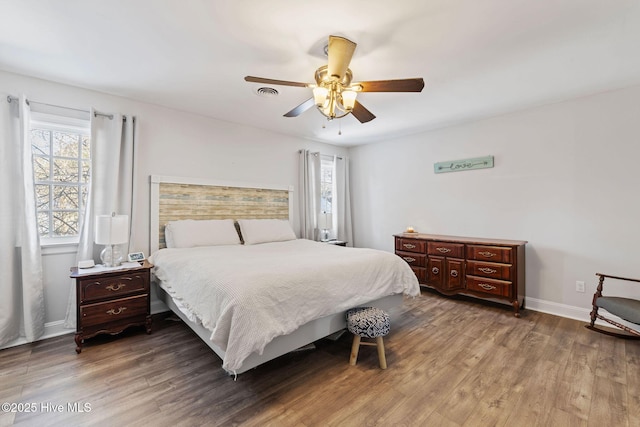 bedroom with multiple windows, wood finished floors, visible vents, and baseboards