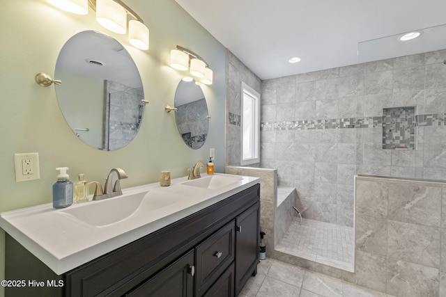 bathroom featuring double vanity, walk in shower, a sink, and tile patterned floors