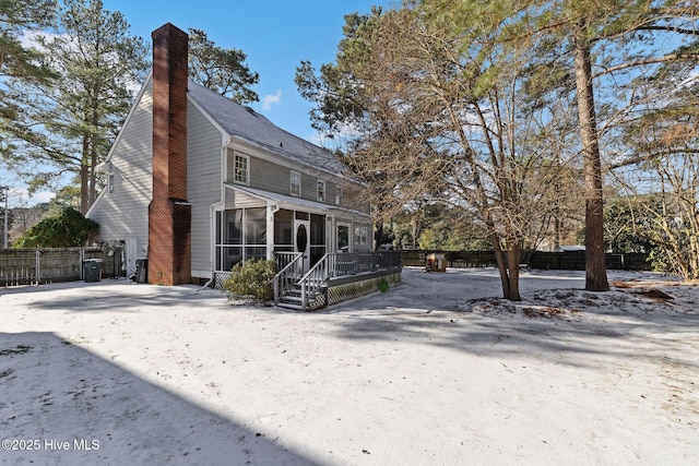 back of house featuring a chimney, fence, and a sunroom