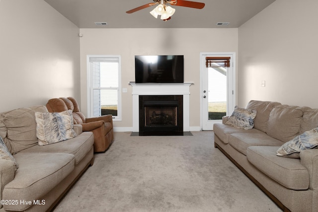 living room featuring a fireplace with flush hearth, visible vents, carpet floors, and ceiling fan