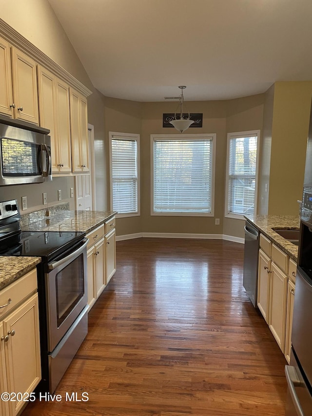 kitchen featuring appliances with stainless steel finishes, vaulted ceiling, dark wood finished floors, and light stone counters