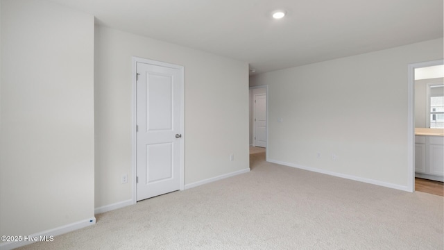 unfurnished bedroom with light carpet and ensuite bath