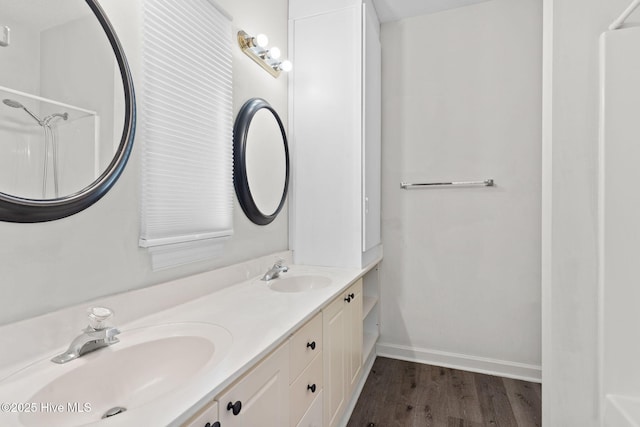 full bathroom with baseboards, wood finished floors, a sink, and double vanity