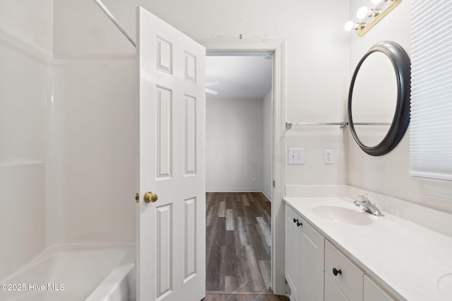 bathroom featuring baseboards, wood finished floors, vanity, and bathtub / shower combination