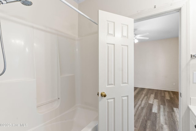 bathroom with baseboards, shower / bathtub combination, wood finished floors, and ceiling fan