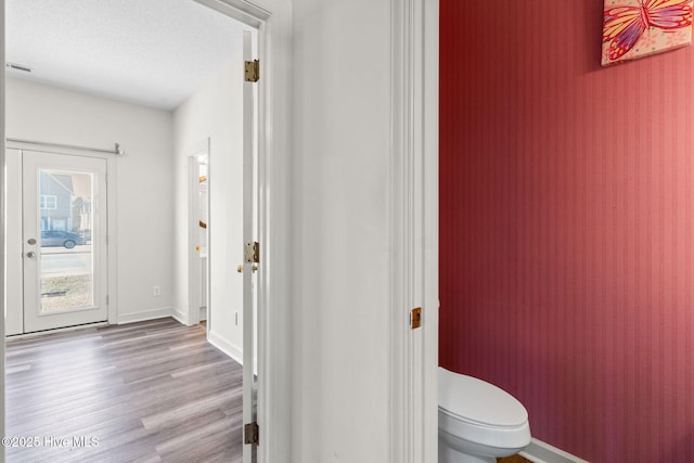 bathroom with wood finished floors, visible vents, toilet, and baseboards