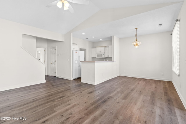 unfurnished living room with baseboards, dark wood-style flooring, visible vents, and ceiling fan with notable chandelier
