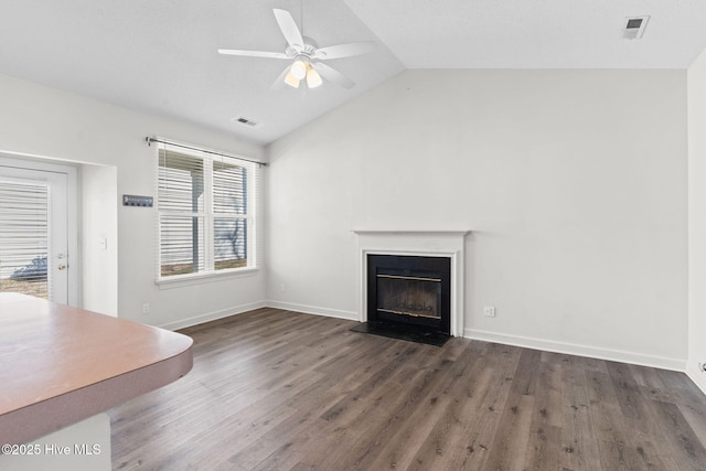 unfurnished living room with a glass covered fireplace, visible vents, lofted ceiling, a ceiling fan, and wood finished floors