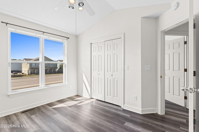 unfurnished bedroom with dark wood-style floors, lofted ceiling, visible vents, and a closet