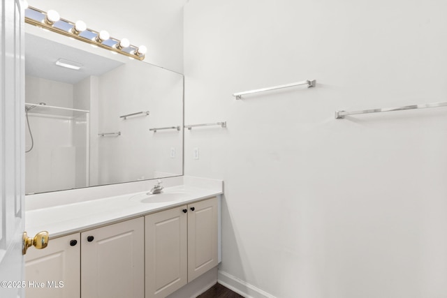 full bath featuring baseboards, vanity, and a shower