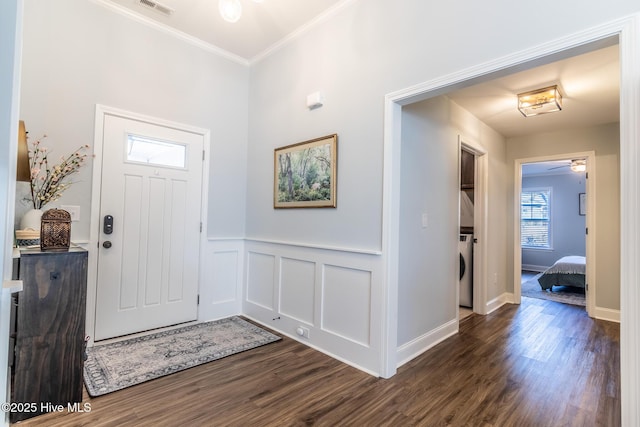 foyer entrance featuring dark hardwood / wood-style flooring, ornamental molding, ceiling fan, and washer / dryer