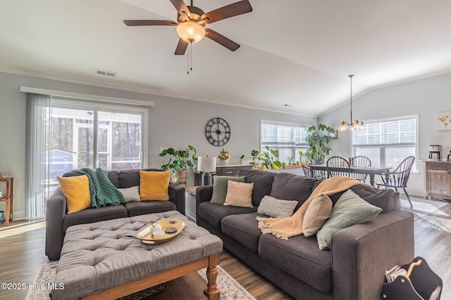 living room with hardwood / wood-style flooring, crown molding, lofted ceiling, and ceiling fan with notable chandelier