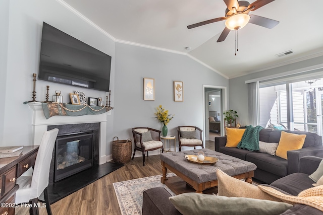 living room with a fireplace, vaulted ceiling, ceiling fan, dark wood-type flooring, and crown molding