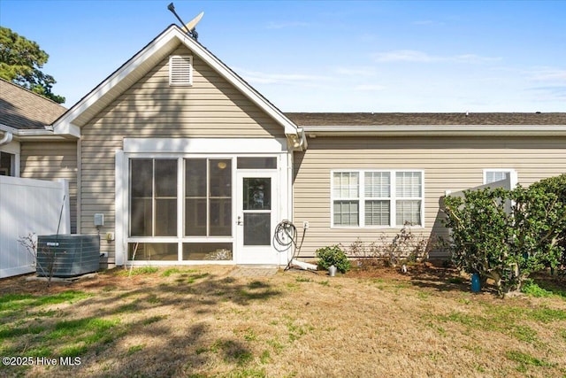 rear view of house featuring a sunroom, a lawn, and central AC unit