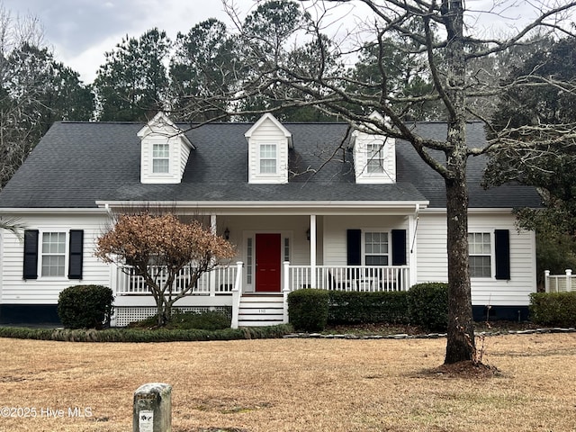 cape cod home with covered porch, a front lawn, and a shingled roof