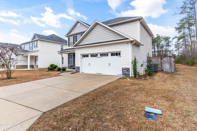 craftsman house with concrete driveway, stone siding, an attached garage, cooling unit, and a front yard