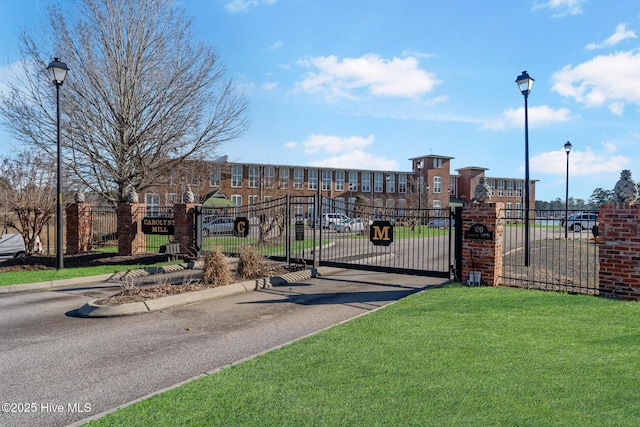 view of gate with fence and a lawn