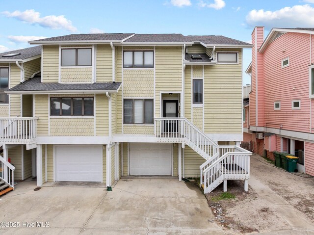 townhome / multi-family property featuring a garage, driveway, and a shingled roof