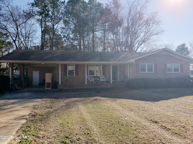 ranch-style home featuring a porch, brick siding, driveway, a carport, and a front lawn