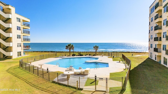 view of pool with a water view, a patio, and a lawn