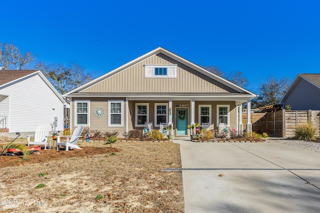 bungalow-style home featuring covered porch, fence, and board and batten siding