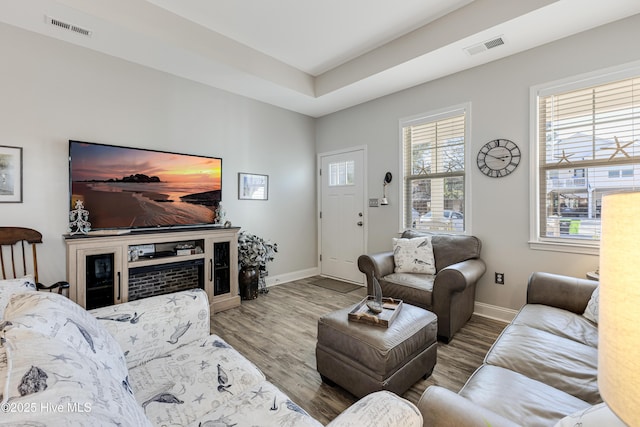 living area with wood finished floors, visible vents, and baseboards