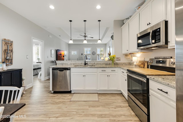 kitchen with a ceiling fan, a peninsula, stainless steel appliances, a sink, and recessed lighting