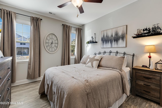 bedroom featuring baseboards, wood finished floors, visible vents, and a ceiling fan