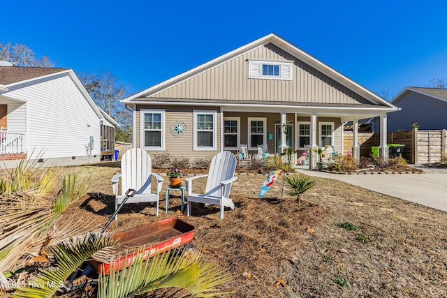 rear view of house with covered porch, fence, and board and batten siding