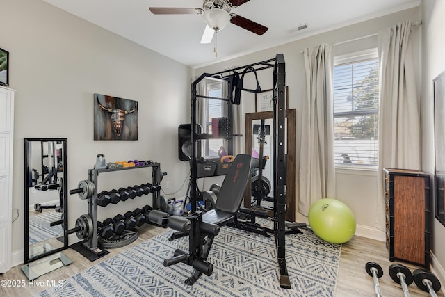 exercise area with light wood-style floors, visible vents, baseboards, and a ceiling fan