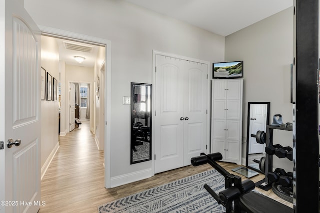 exercise room featuring light wood-style floors, baseboards, and visible vents