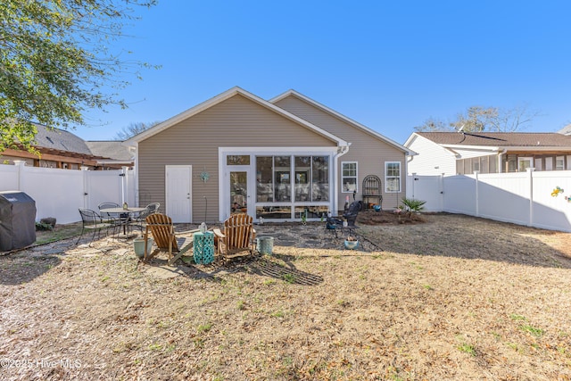 back of house with a sunroom, a lawn, a fenced backyard, and a gate