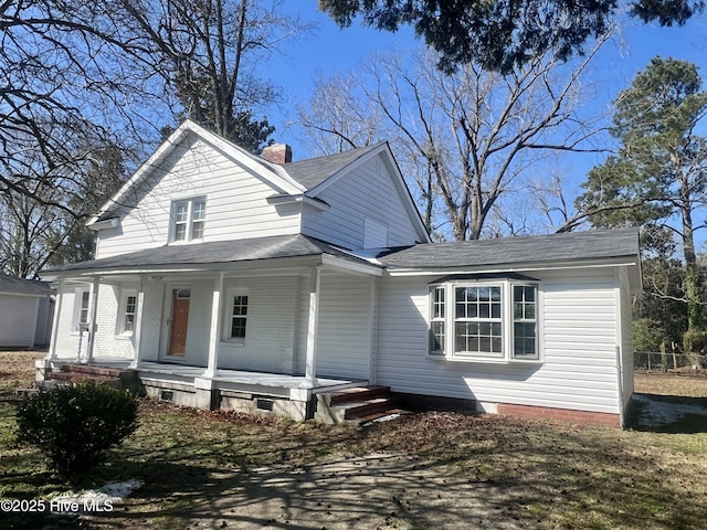 view of front facade featuring a porch, brick siding, and a chimney