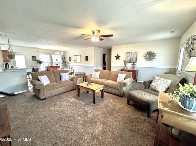 carpeted living area with visible vents, a textured ceiling, and ceiling fan with notable chandelier