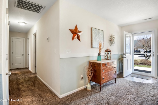 entryway featuring carpet, visible vents, a textured ceiling, and baseboards