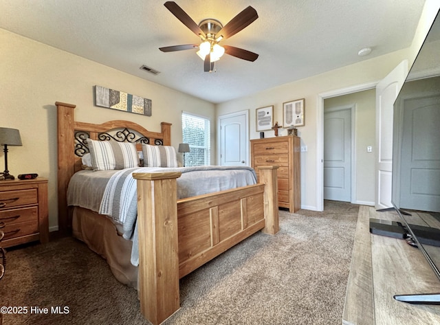 bedroom featuring visible vents, dark carpet, a textured ceiling, and ceiling fan