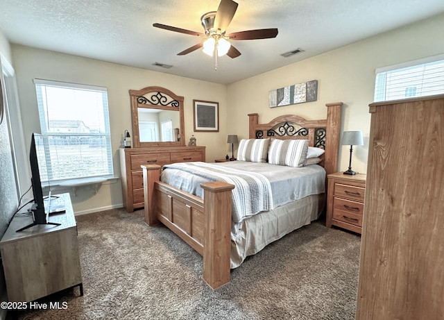 bedroom with visible vents, multiple windows, dark carpet, and a textured ceiling