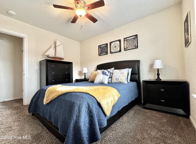 bedroom featuring ceiling fan, dark carpet, and a textured ceiling