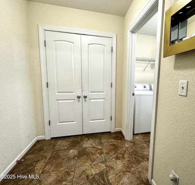 hallway with a textured wall, washer / clothes dryer, and baseboards