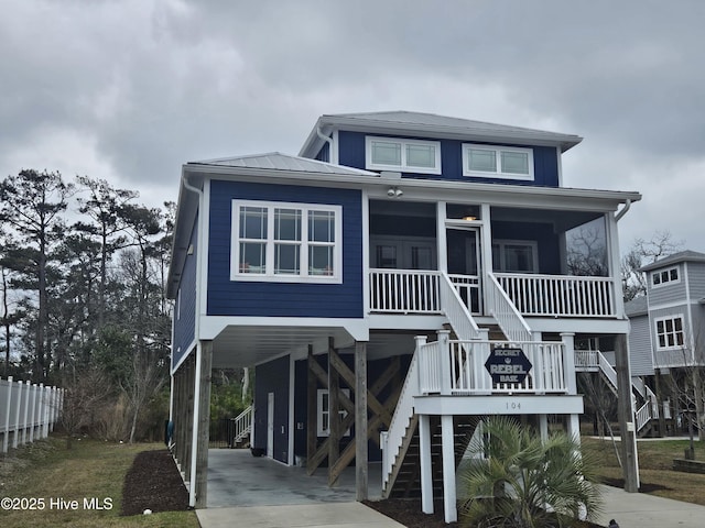 beach home with driveway, a sunroom, metal roof, stairs, and a carport