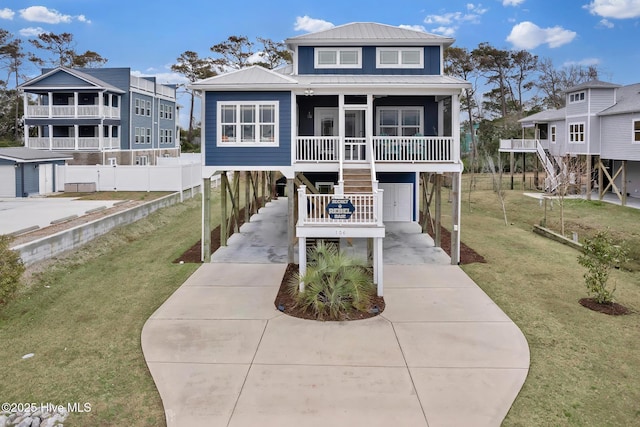 raised beach house featuring concrete driveway, a sunroom, stairway, metal roof, and a carport