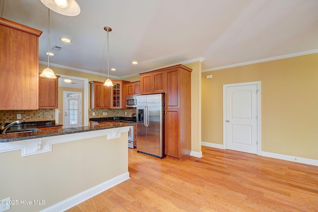 kitchen featuring appliances with stainless steel finishes, glass insert cabinets, brown cabinetry, a sink, and a peninsula