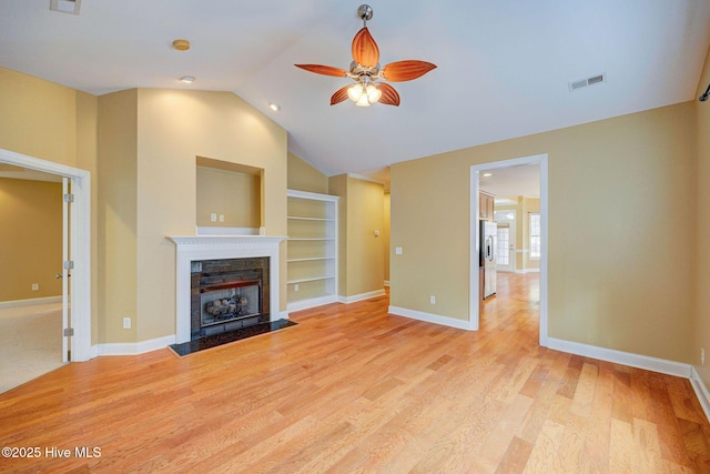 unfurnished living room featuring light wood finished floors, visible vents, a fireplace with flush hearth, ceiling fan, and baseboards