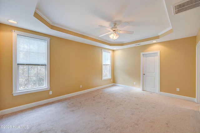 empty room featuring carpet floors, visible vents, baseboards, ornamental molding, and a tray ceiling